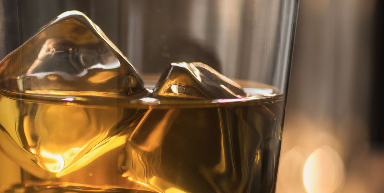 glass with bourbon and ice cubes